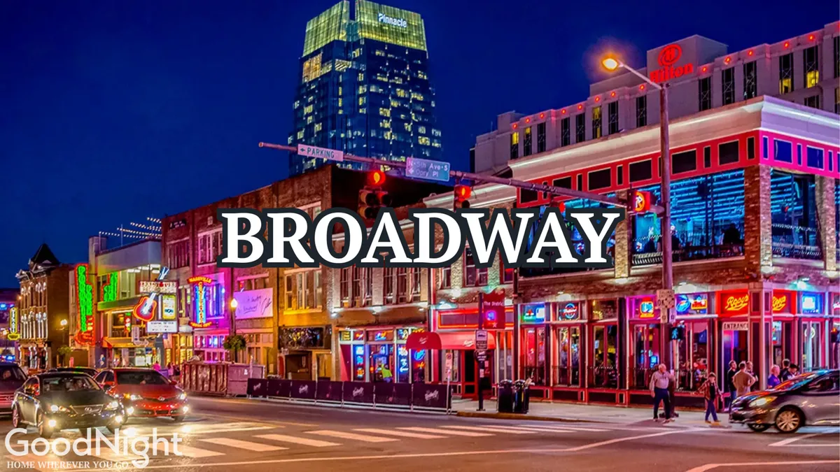 A lively nighttime street scene in downtown Nashville, with glowing neon signs, bustling crowds, illuminated windows, and a vibrant urban atmosphere. The photo captures the city’s energetic nightlife and the excitement of live music, dining, and entertainment just steps away from the property.